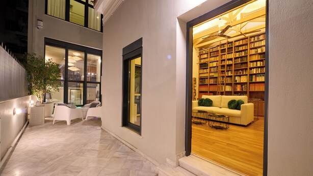Un edificio moderno con interior luminoso, una escalera visible y un área de descanso con sofá y sillones.