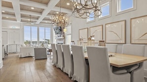 A spacious dining area with a long table, cushioned chairs, and pendant lighting. - ☀️Luxury-Gulf Views-Bikes-Rooftop Lounge & Golf Cart-Caspian Escape☀️ (Santa Rosa Beach)