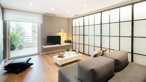 Un salon moderne avec un téléviseur à écran plat, une table basse blanche et un canapé gris.