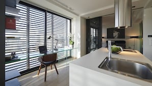 A modern kitchen with a large island, stainless steel appliances, and a view through floor-to-ceiling windows.