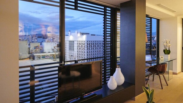 A modern living room with large windows, a fireplace, and a view of the cityscape.