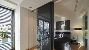 A modern bedroom with a sliding glass door leading to a balcony, a bed with a geometric-patterned headboard, and a minimalist decor style.