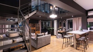 Un intérieur moderne comprenant un escalier, un canapé, un coin repas et une cuisine.