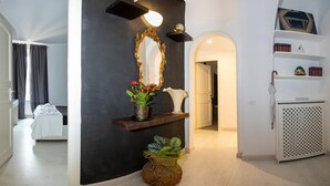 A hotel hallway with a bed, a mirror, a shelf with decorative items, and a plant. - Babuino Luxury Design Apartment (Roma)