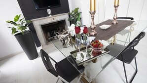 A modern dining area with a glass table, black chairs, a fireplace, and decorative items like roses and candles. - Babuino Luxury Design Apartment (Roma)
