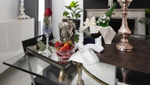 A modern living room with a glass dining table, a TV mounted on the wall, and a fireplace. - Babuino Luxury Design Apartment (Roma)