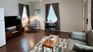 Ein Wohnzimmer mit Sofa, Couchtisch, Fernseher und einem Essbereich mit Tisch und Stühlen.