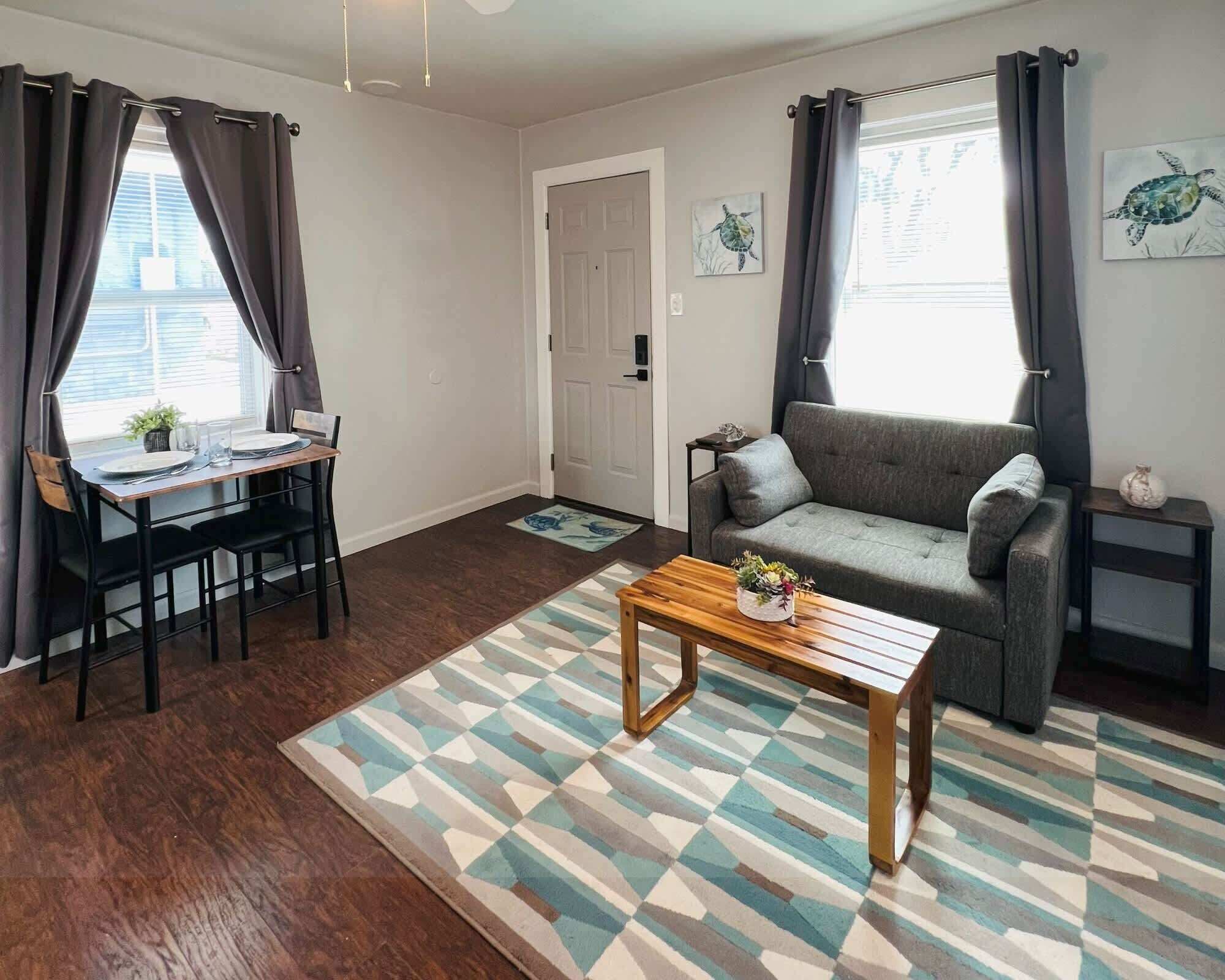 Un salon comprenant un canapé, une table basse, une table à manger avec des chaises et une porte.