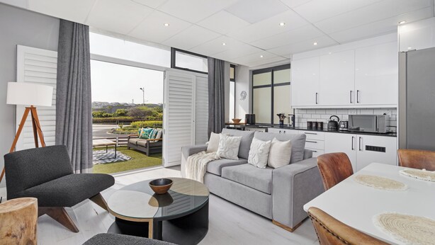 Een moderne woonkamer met een grijze bank, een bijzettafeltje en een eettafel met placematen.