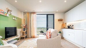 A modern living room with a sofa, TV, and a view to the outside. - The Eades Laura Perryman 1 Bed (London)