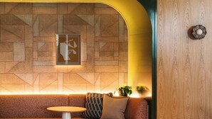 A modern living room with a wooden accent wall, a round table, and a sofa. - The Eades ADC Atelier 2 Bed (London)