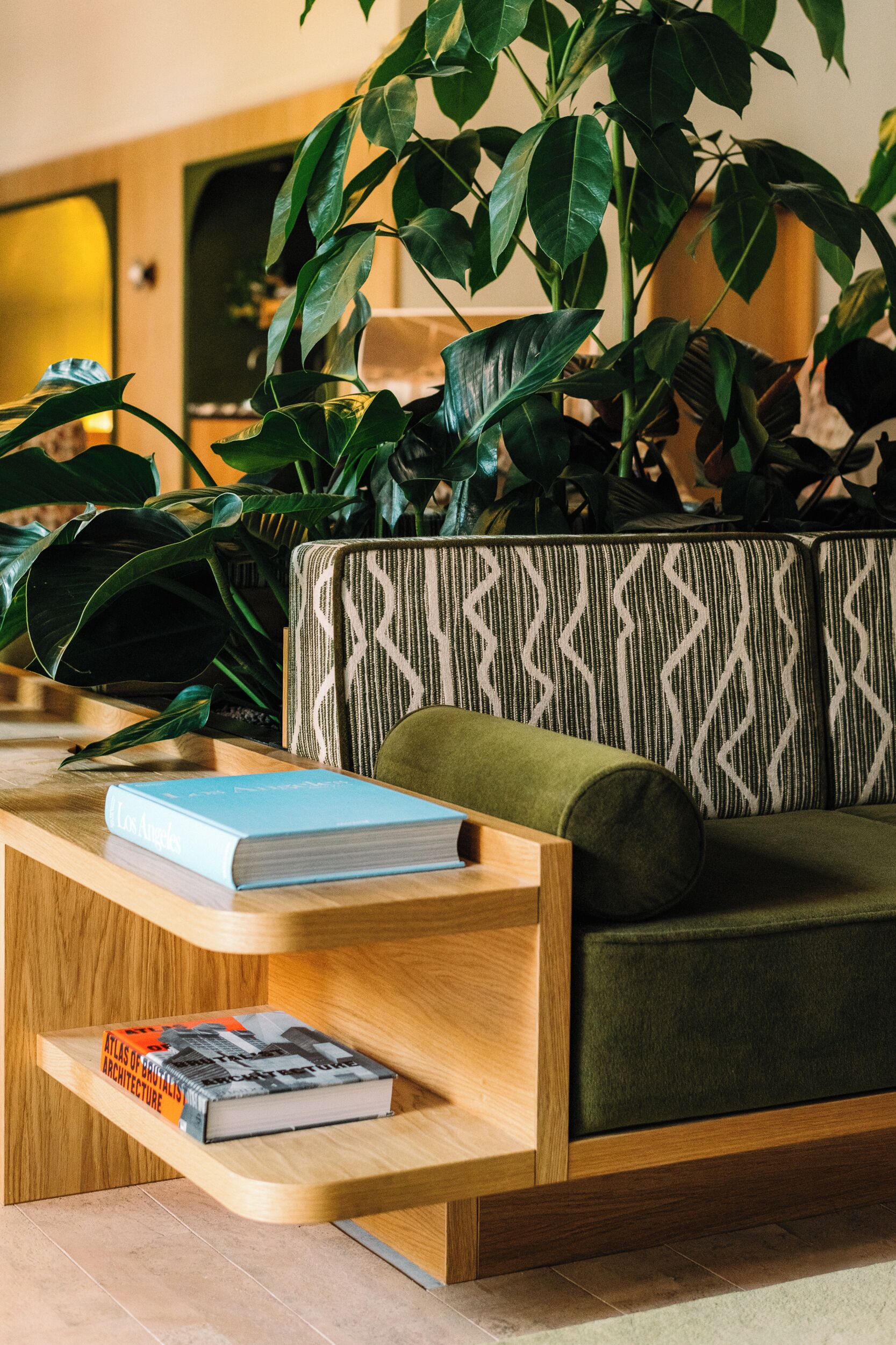Un salon moderne avec un canapé vert, une table basse en bois et un coussin à motifs.