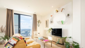 Uma sala de estar moderna com sofá, mesa de centro, televisão e plantas.