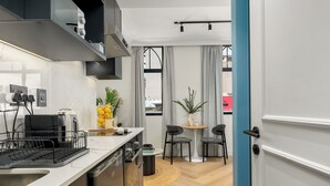 Una cocina moderna equipada con lavavajillas, cafetera y una pequeña zona de comedor con dos sillas y una mesa.