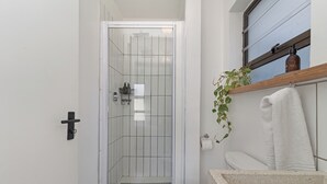 Un baño con cabina de ducha de vidrio, inodoro y lavabo con encimera color beige.