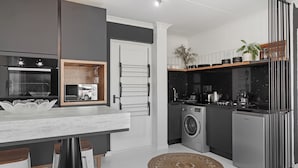 Una cocina moderna con horno Bosch, lavadora y cafetera Moka.