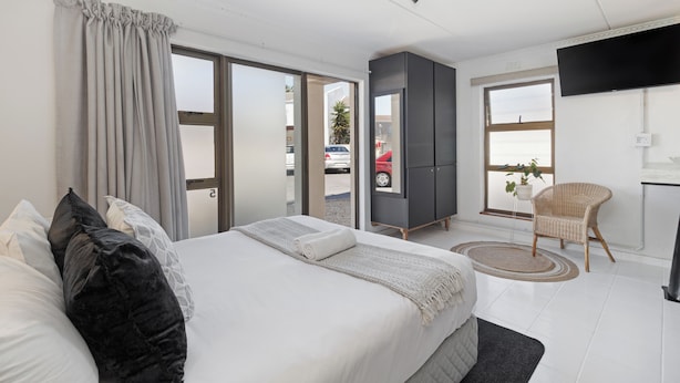 Una habitación de hotel moderna con una cama grande, un televisor de pantalla plana, un armario y vistas al exterior.