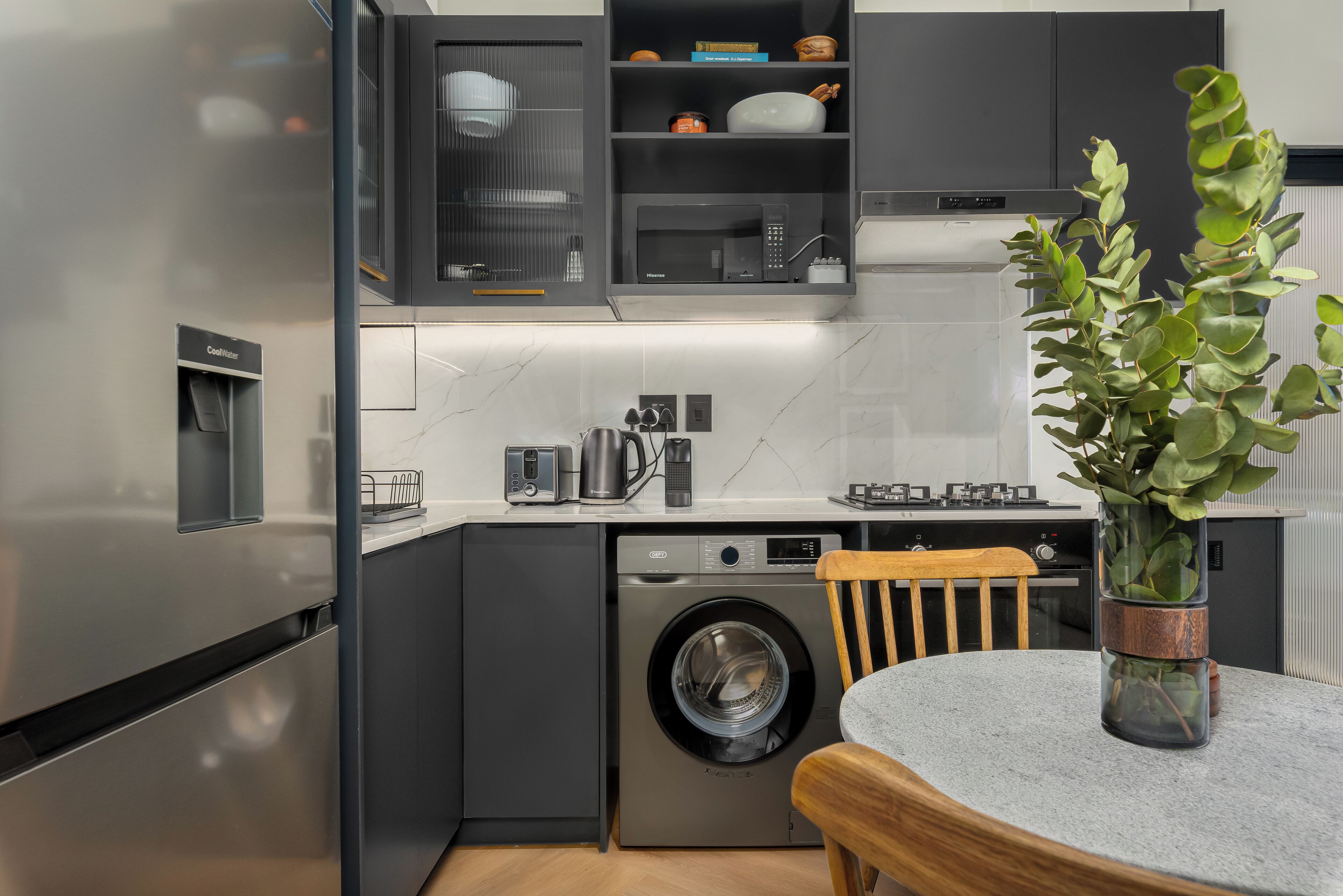 A modern kitchen with a built-in washer and dryer, stainless steel appliances, and a dining area with a table and chairs.
