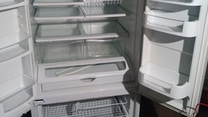 Et åbent køleskab med flere hylder og et fryserum.