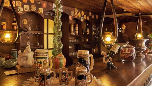 Un espace bar décoré de bois, avec des choppes à bière d’époque et une variété de bouteilles et de verres.
