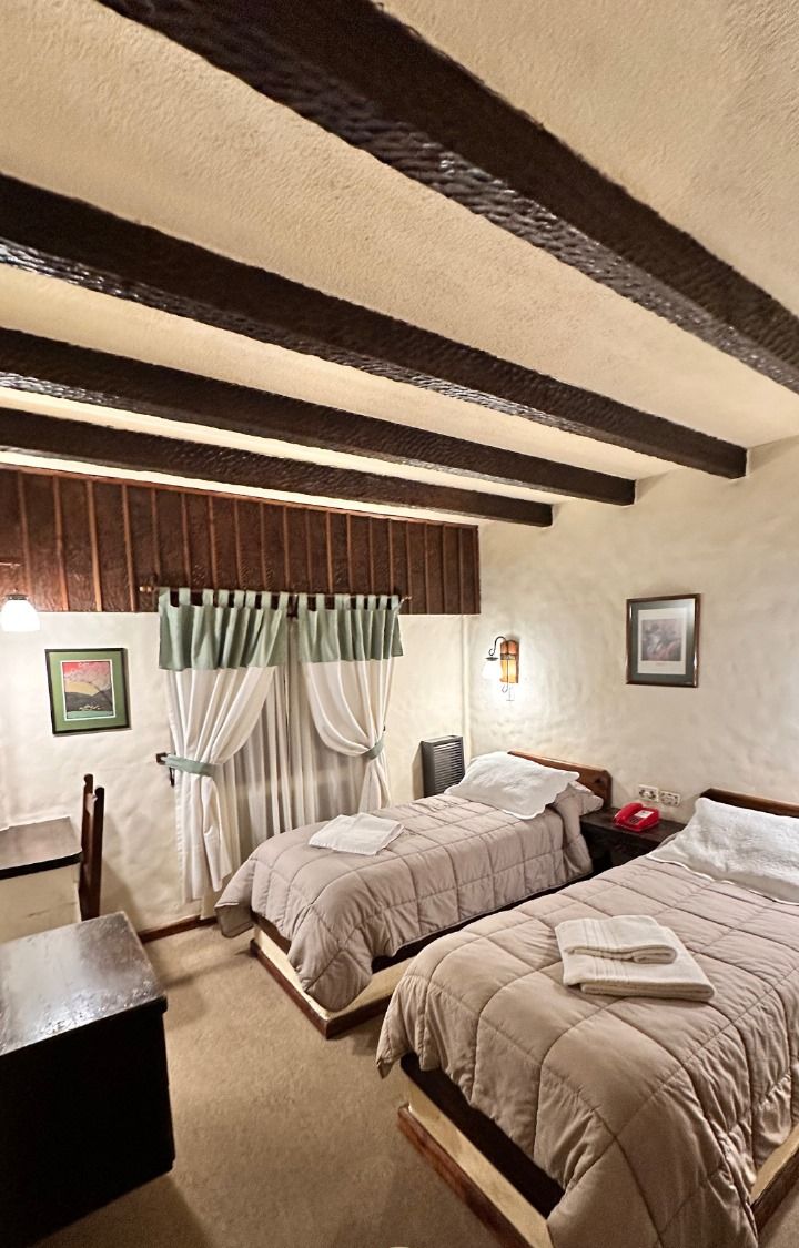 Una habitación acogedora con dos camas, un escritorio y una mesita de noche con lámpara.