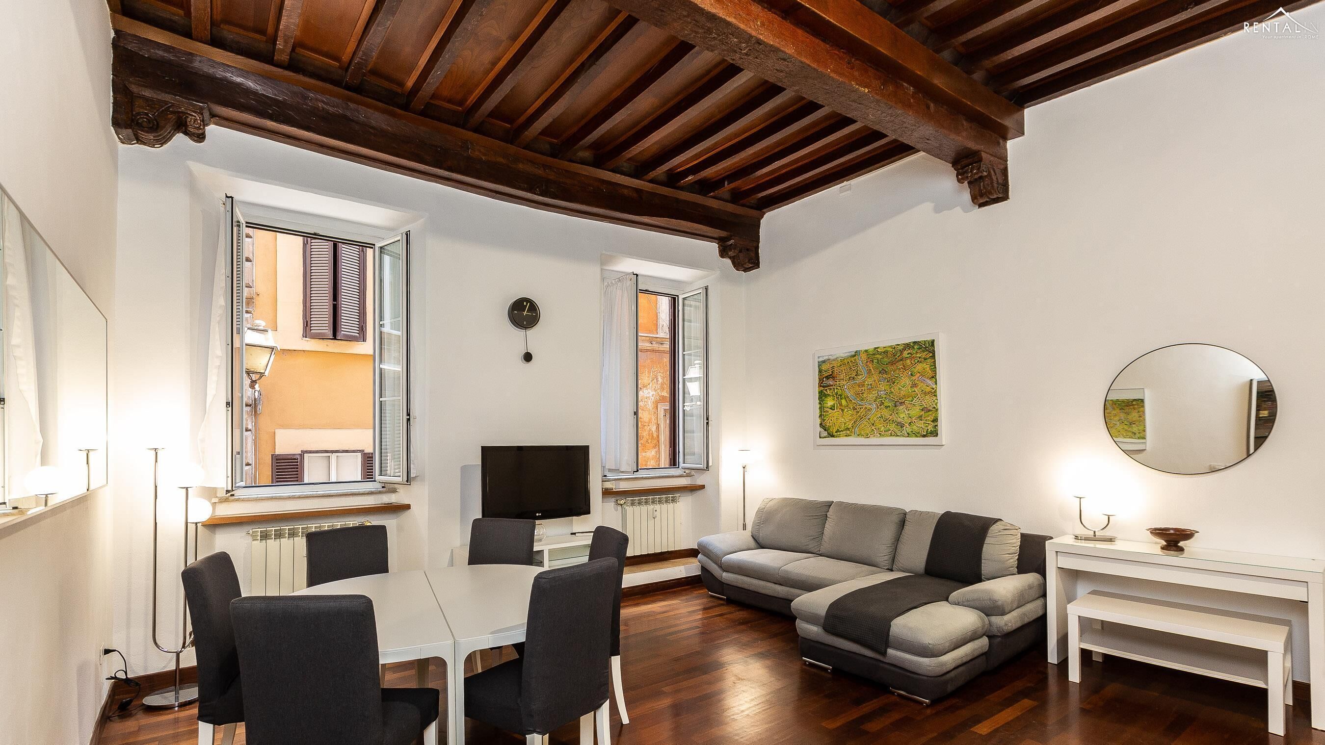 A furnished living room with a dining table, chairs, a sofa, and a TV.