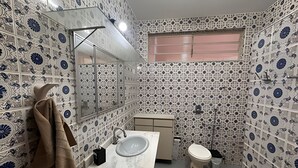 A bathroom with patterned walls, a sink, a toilet, and a towel hanging on the wall. - Casa Refúgio Verde Conforto em SJBVista (São João da Boa Vista)