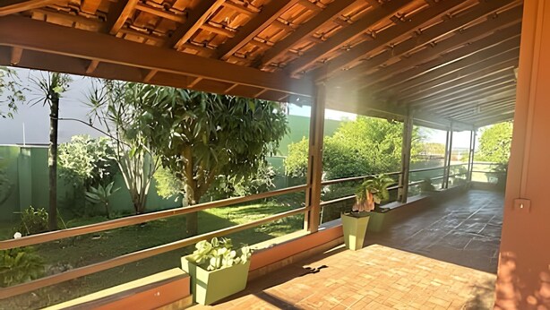 Ein überdachter Außenbereich mit Blick auf einen Garten und ein Gewässer.