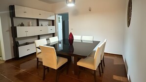 Ein Essbereich mit einem rechteckigen Tisch, sechs Stühlen und einer Pendelleuchte.