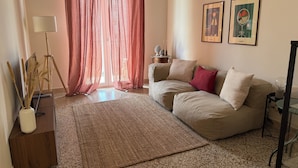 A living room with a beige sofa, a patterned rug, and two framed artworks on the wall.
