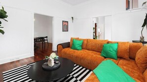 A living room with a sofa, a dining area with chairs, and a black coffee table. - The Ultimate Bedford Modern Stay (Bedford)
