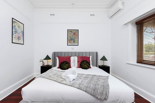Drift off in this stylish, serene bedroom featuring a plush bed, elegant gray velvet headboard, and A/C for a perfect night's sleep.