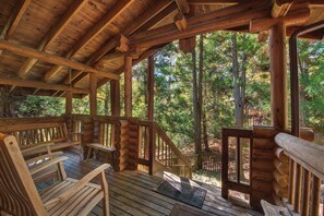 Eine Holzterrasse mit Bänken und einer Treppe, die in einen Wald führt.