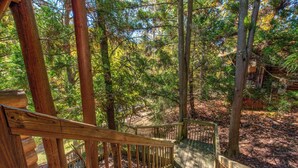 A wooden staircase leading to a deck surrounded by trees.