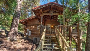 A log cabin with a wooden staircase leading to a porch.