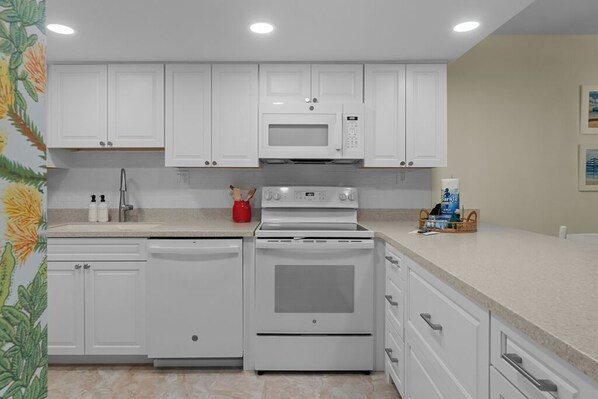 A kitchen with white cabinets, a microwave, an oven, and a dishwasher.