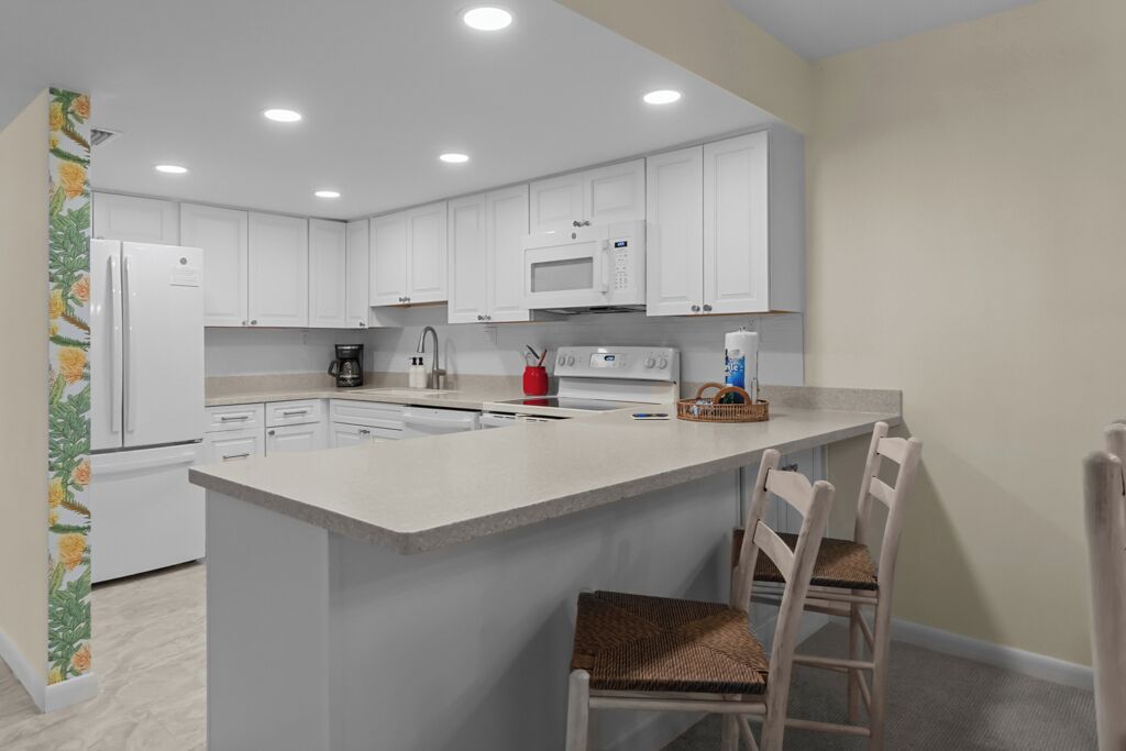 A modern kitchen with white cabinets, a central island, and a microwave.