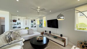 Een moderne woonkamer met een witte bank, een zwarte salontafel en een aan de muur bevestigde televisie.