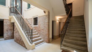 Un intérieur à plusieurs niveaux, avec un escalier, des murs en pierre et un sol carrelé.