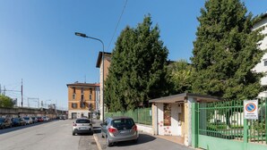A street view with parked cars, a green gate, and a building with a sign.