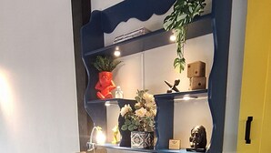 A modern workspace with a desk, chair, shelves, and a potted plant.