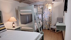 A room with a bunk bed, a desk, a lamp, and a television.