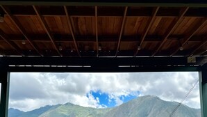 A wooden deck with two red Adirondack chairs facing a mountain view.