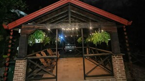 A covered outdoor area with a brick floor, wooden benches, and hanging plants.