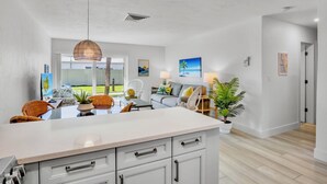 Una cucina moderna con un'isola grande, zona pranzo con sedie e vista sull'esterno.