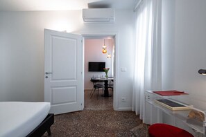 A hotel room with a bed, a desk with a chair, a television, and a dining area with a table and chairs. - Venetian Alcove (Venezia)