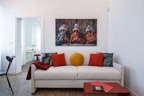 A living room with a sofa, a coffee table, and a painting on the wall.