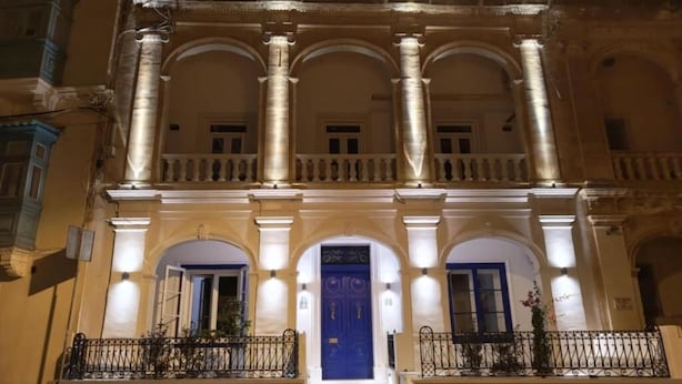 A building with a central blue door, multiple arches, and a balcony with railings. - Alba (Sliema)