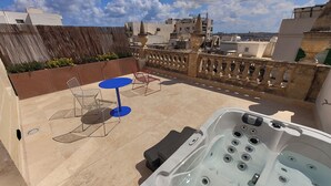 A rooftop terrace with a hot tub, two blue tables, and red chairs. - Alba (Sliema)