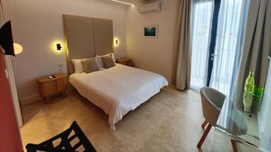 A modern bedroom with a large bed, bedside tables, a chair, and a glass partition. - Alba (Sliema)